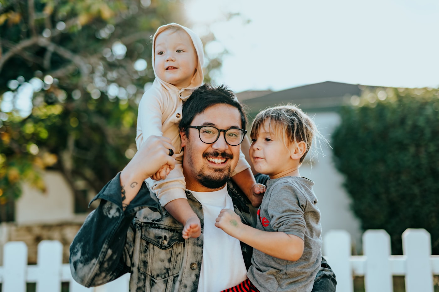 A father holding his two young children outdoors