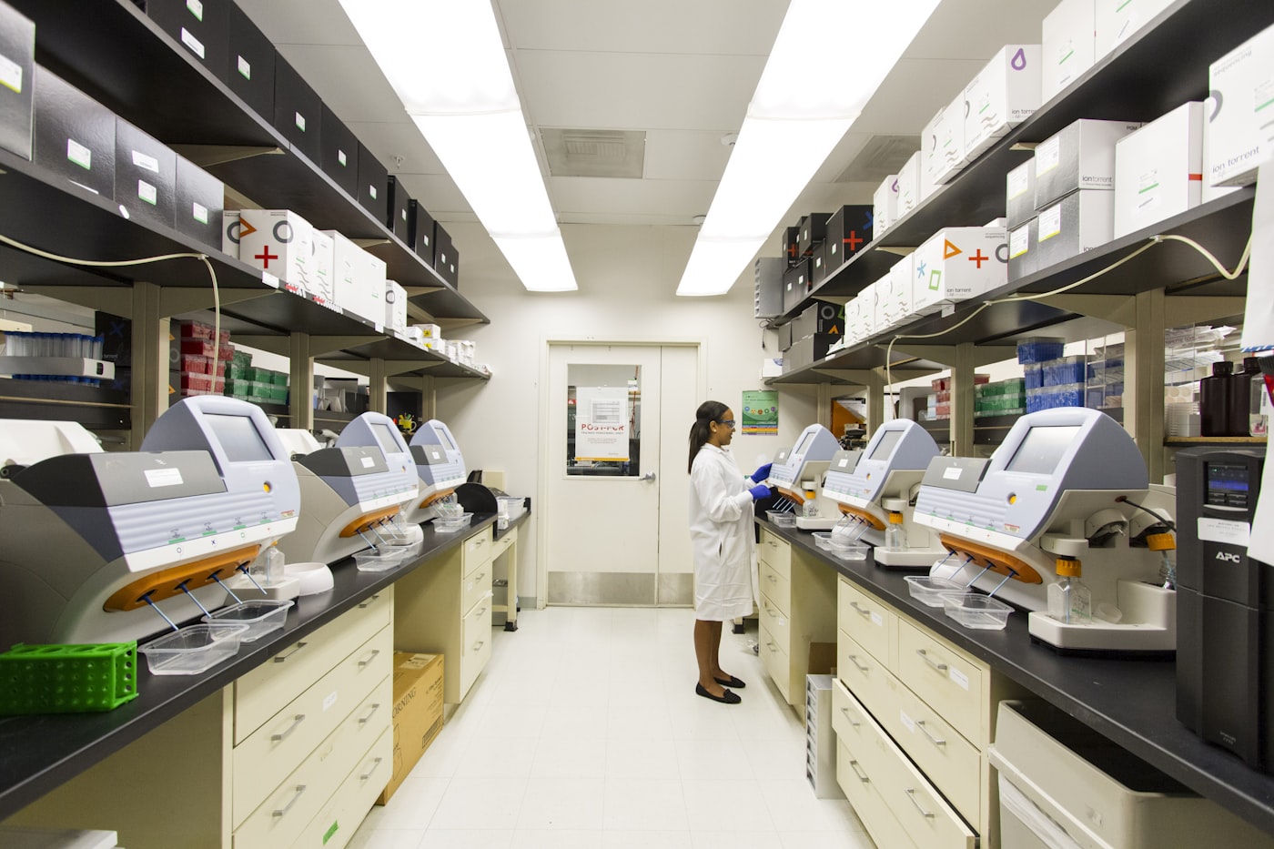 A laboratory technician working between rows of analyzers